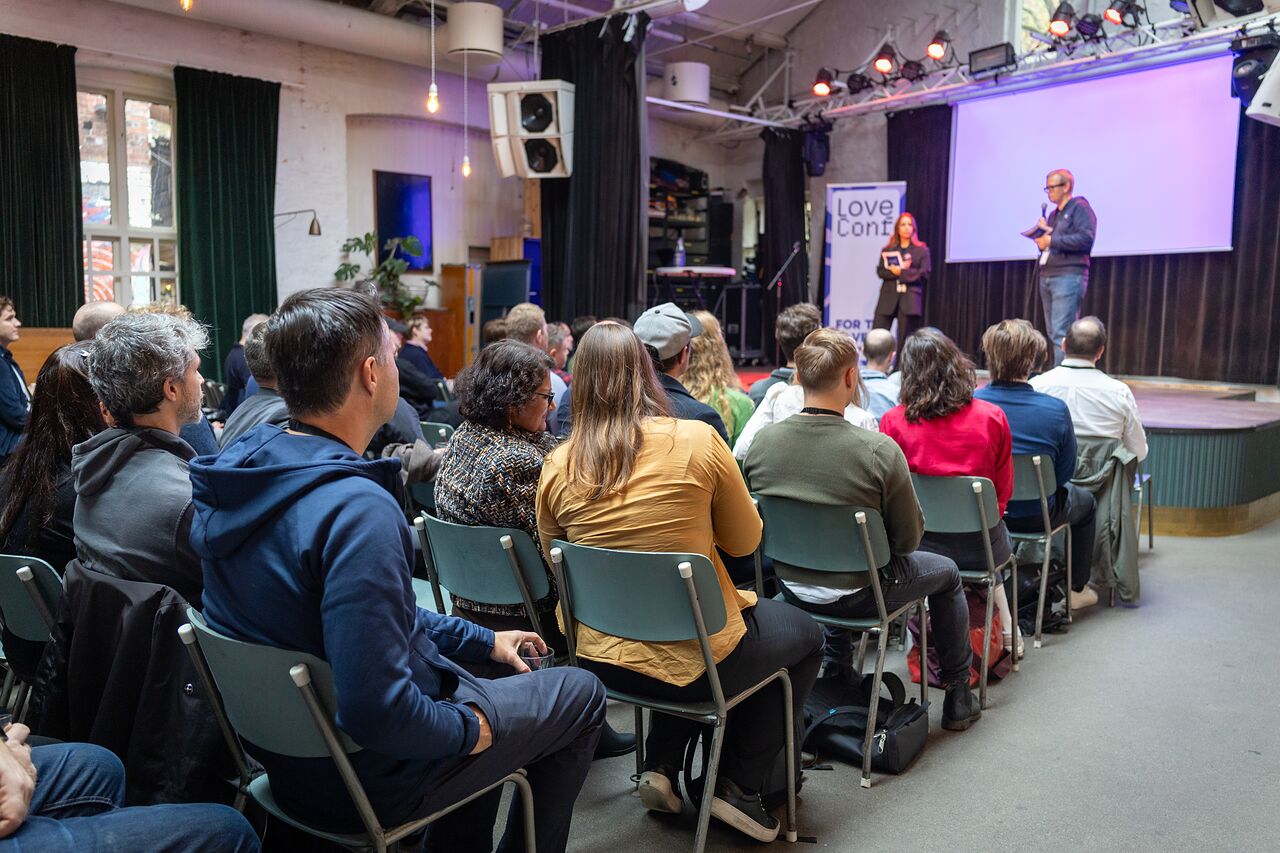 The audience in front of the stage as the hosts open the conference