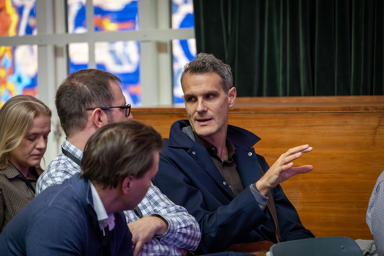 Attendees deep in conversation on a wooden bench